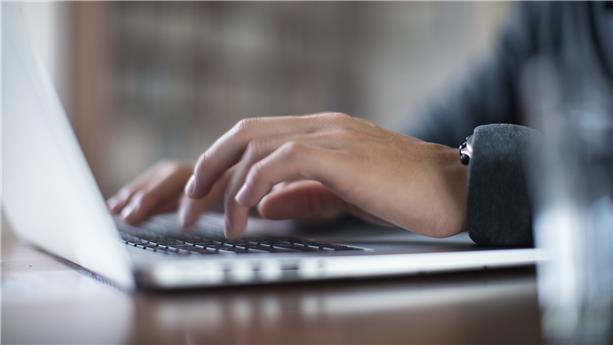 Hands typing on a laptop keyboard