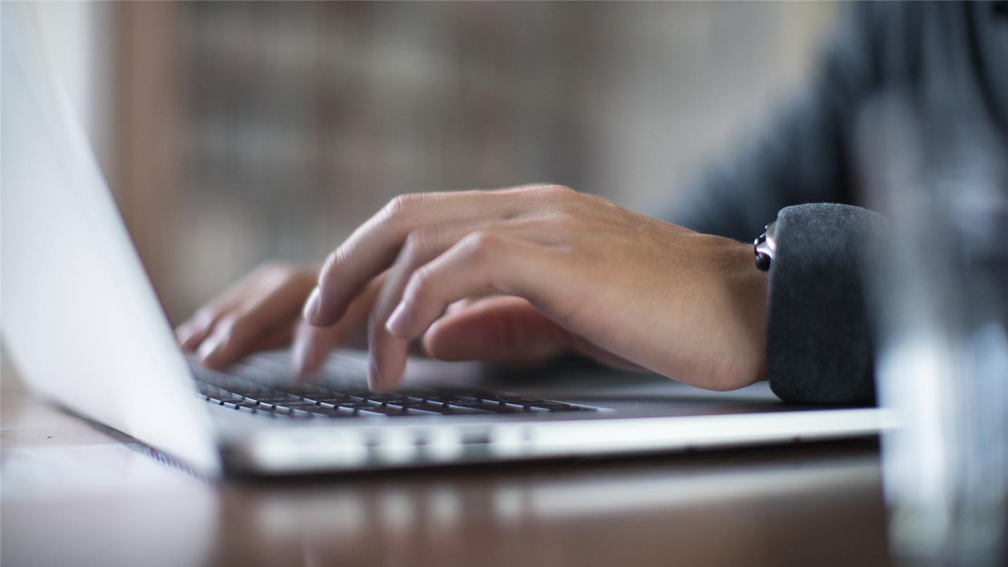 Hands typing on a laptop keyboard